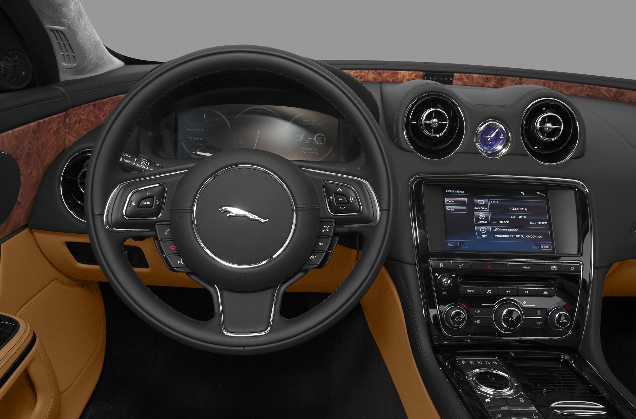 Luxury interior with steering wheel, wood trim dashboard, and digital infotainment display