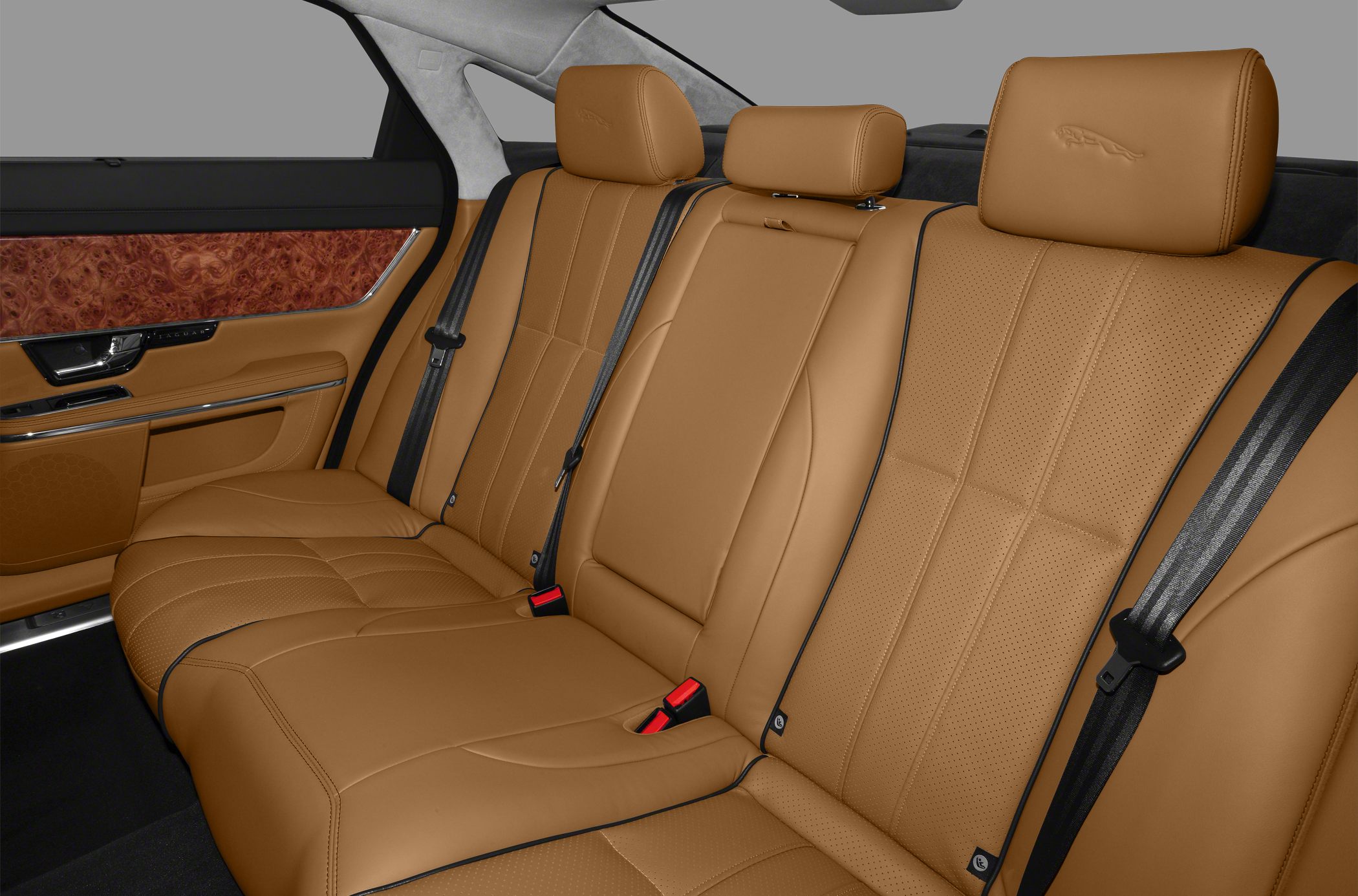Tan leather rear seats with stitching and wood trim in luxury car interior