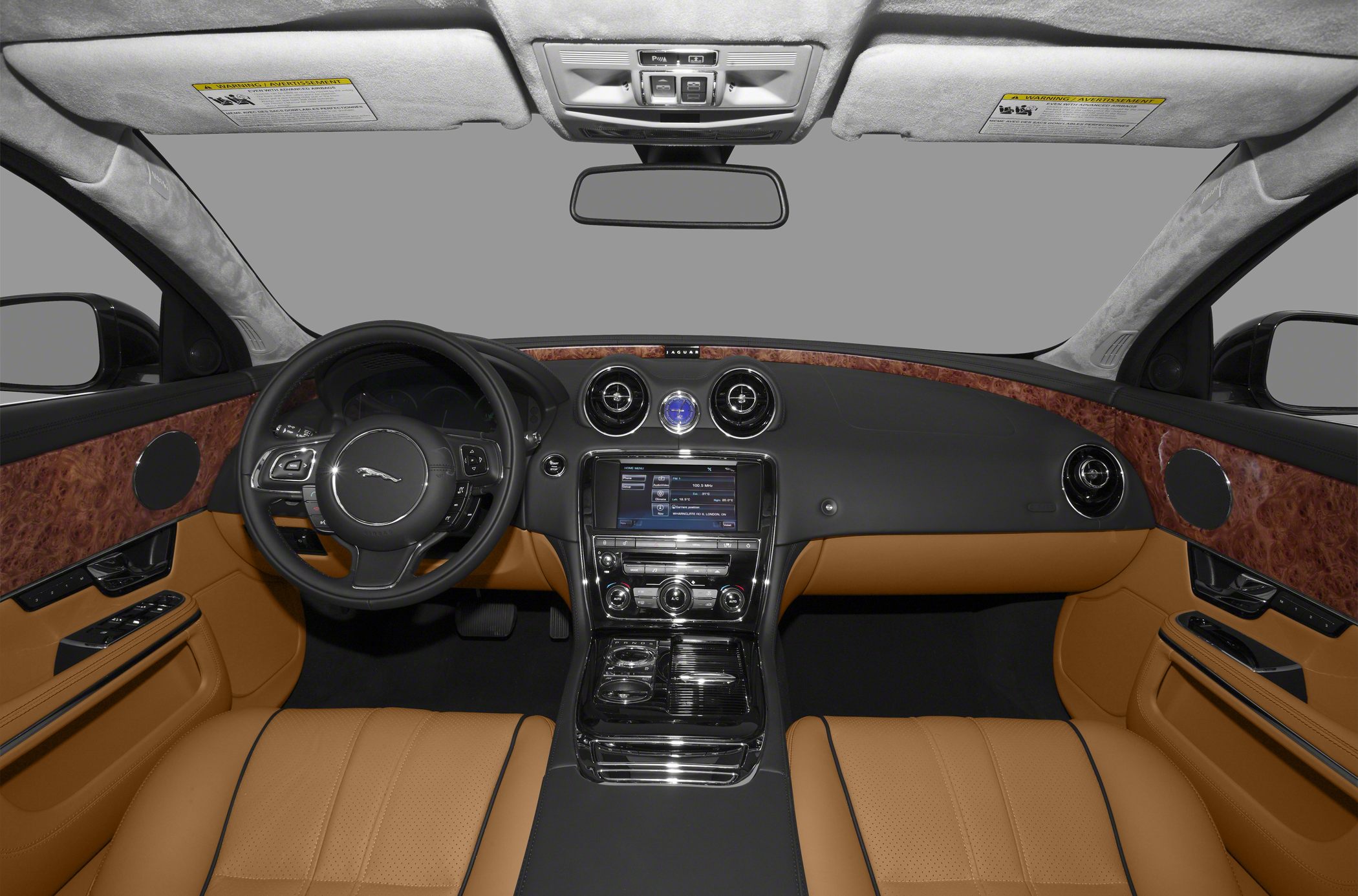 Luxury interior with wood trim, tan leather seats, steering wheel, and infotainment display