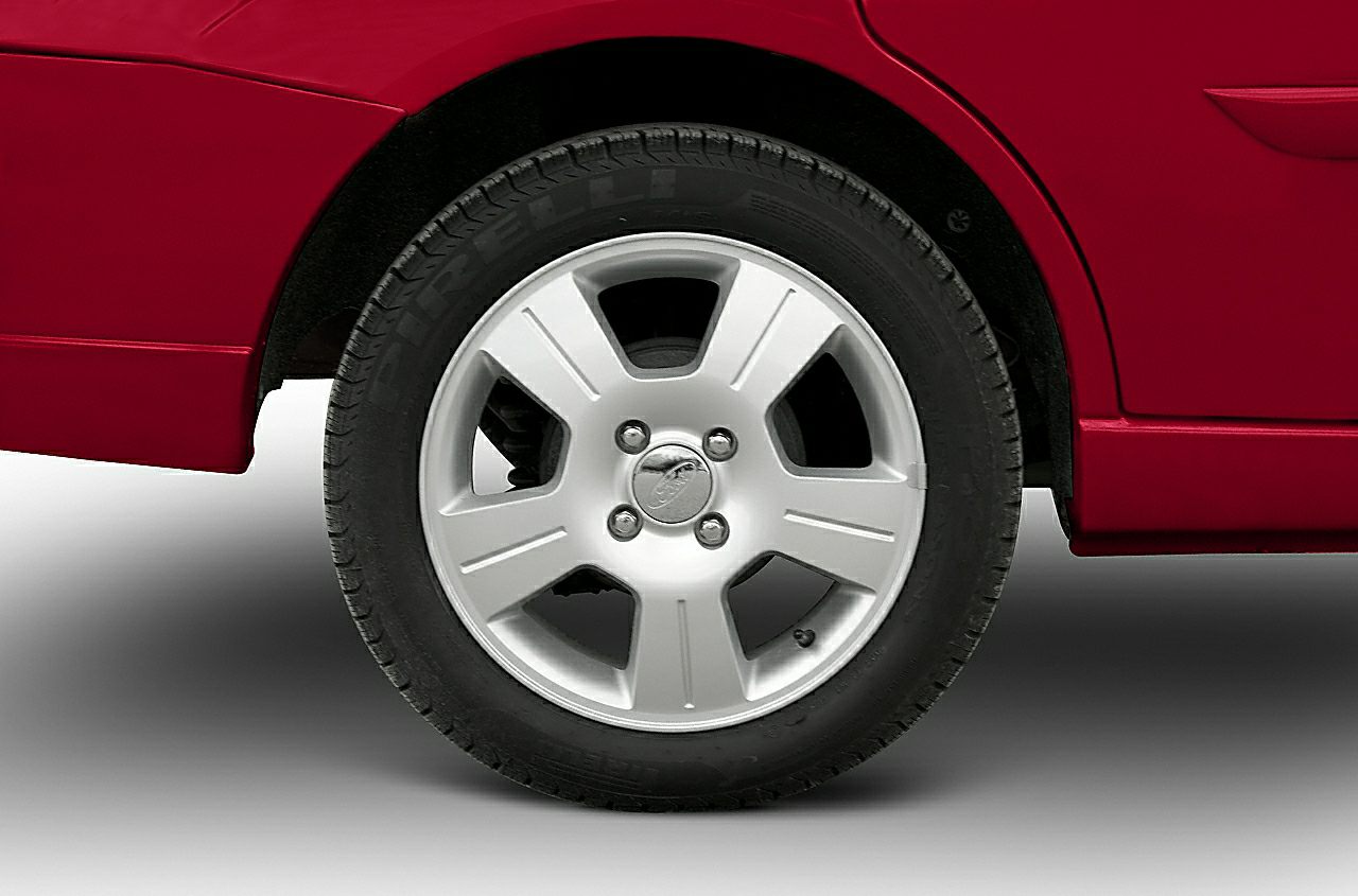 Silver alloy wheel and tire of a car, featuring a five-spoke design.