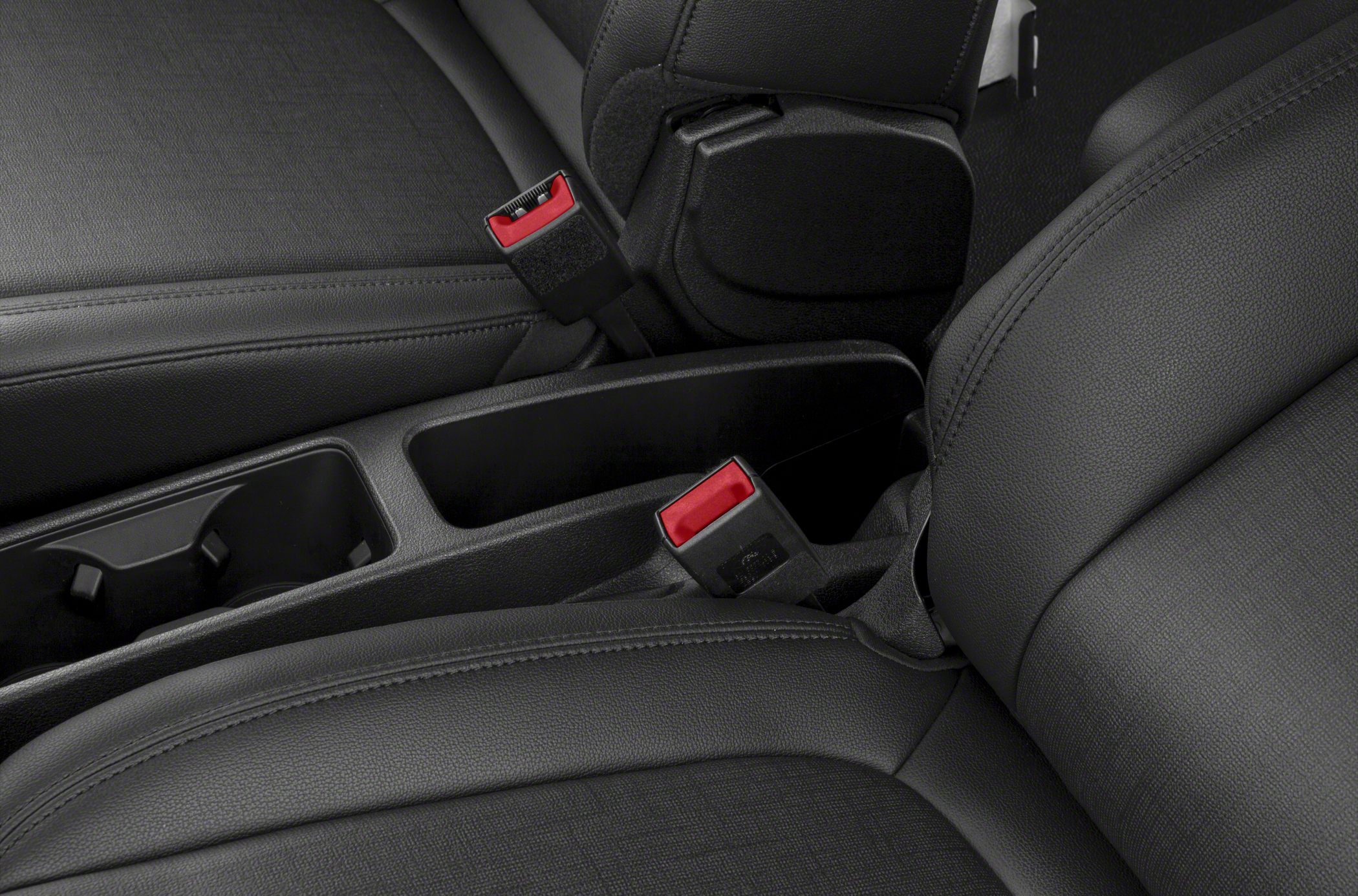 Close-up of seat belts and center console storage in black upholstery.