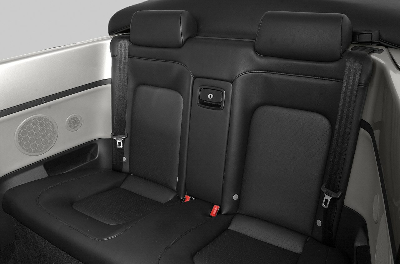 Black leather rear seats with seatbelts and headrests in convertible interior.