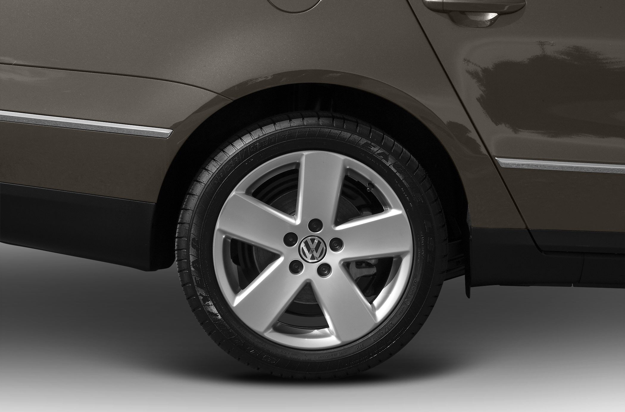 Close-up of five-spoke alloy wheel and tire on a vehicle side panel