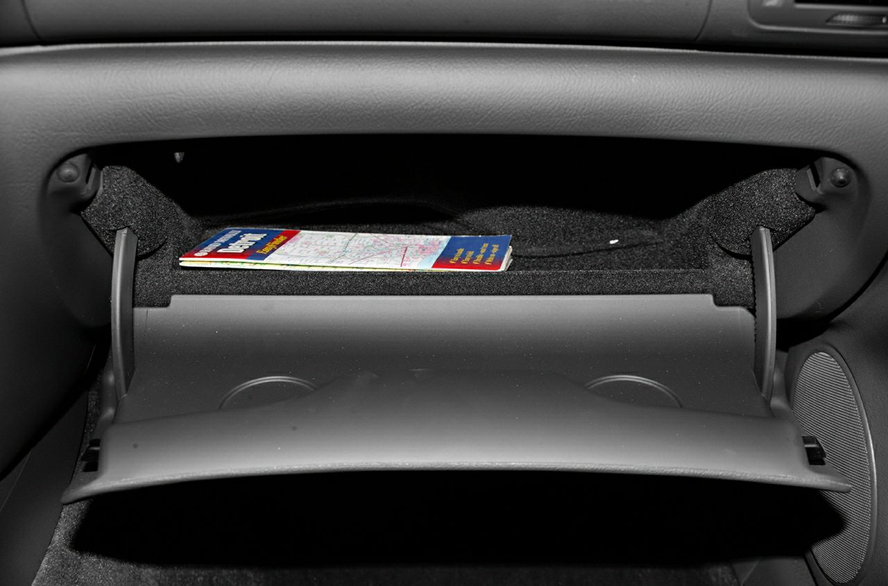 Open glove box storage compartment with map booklet on dashboard