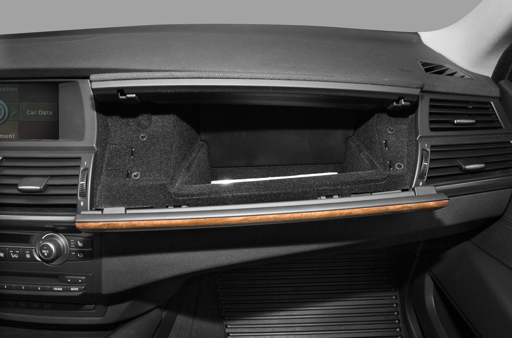 Open glove compartment and dashboard controls with wood trim