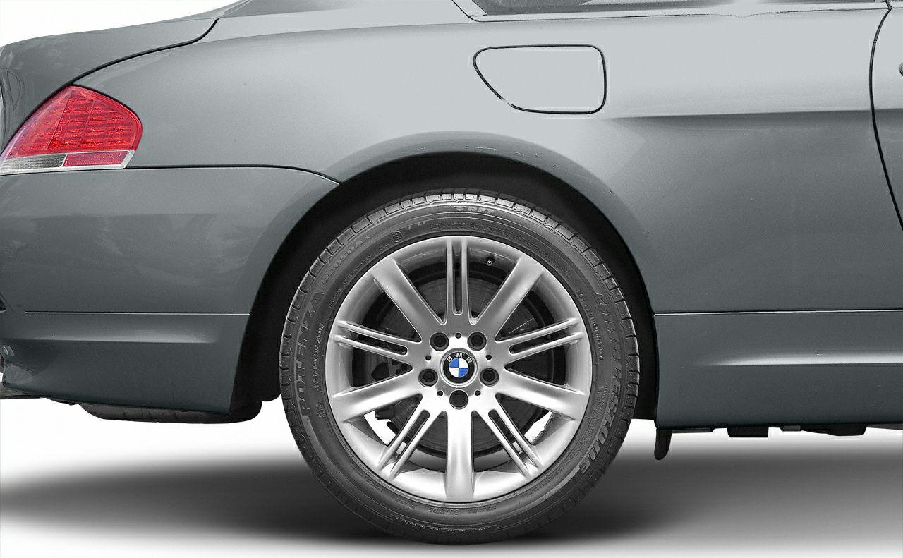 Close-up of rear alloy wheel, tire, and fuel filler on a coupe