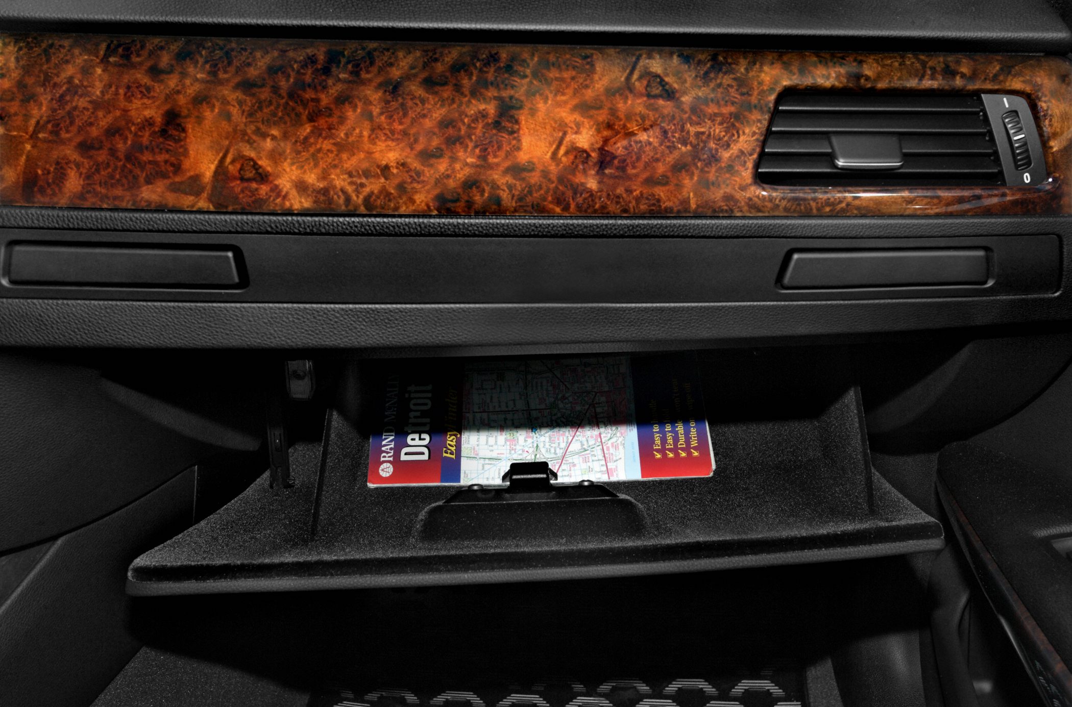 Open glove compartment with wood trim dashboard and air vent