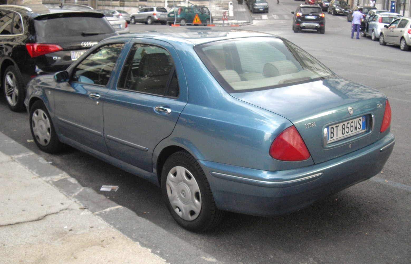 Rear three-quarter view of a blue sedan showing tail lights and side profile