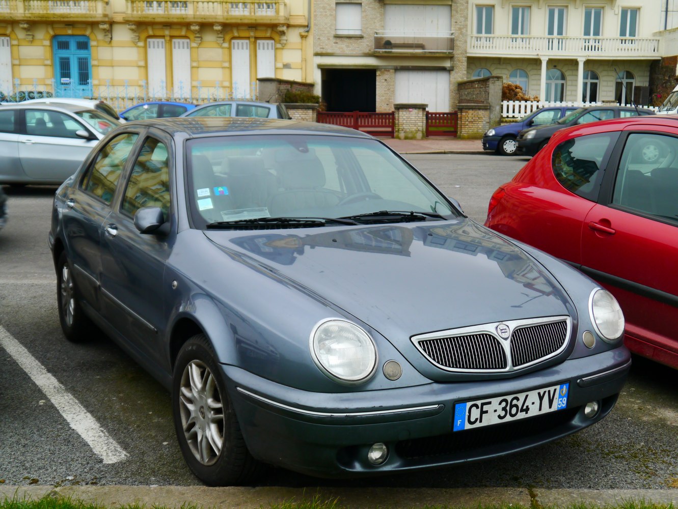 Sedan with oval headlights and vertical grille slats parked.