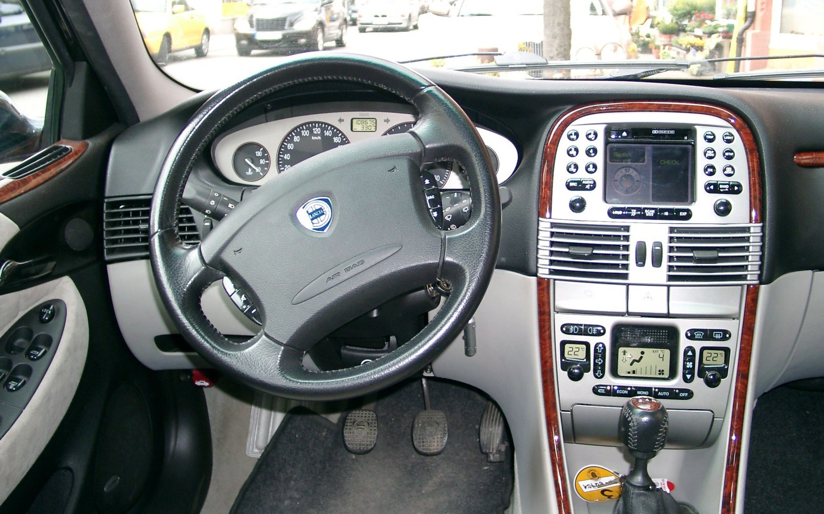 Black leather steering wheel and vintage dashboard console with wood trim