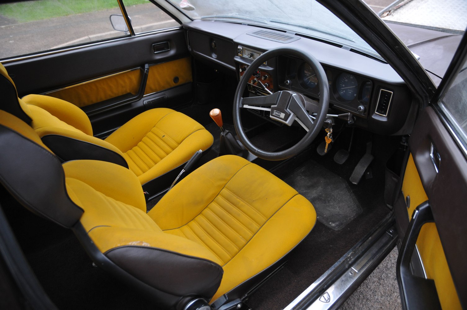 Vintage car interior with yellow bucket seats and classic dashboard