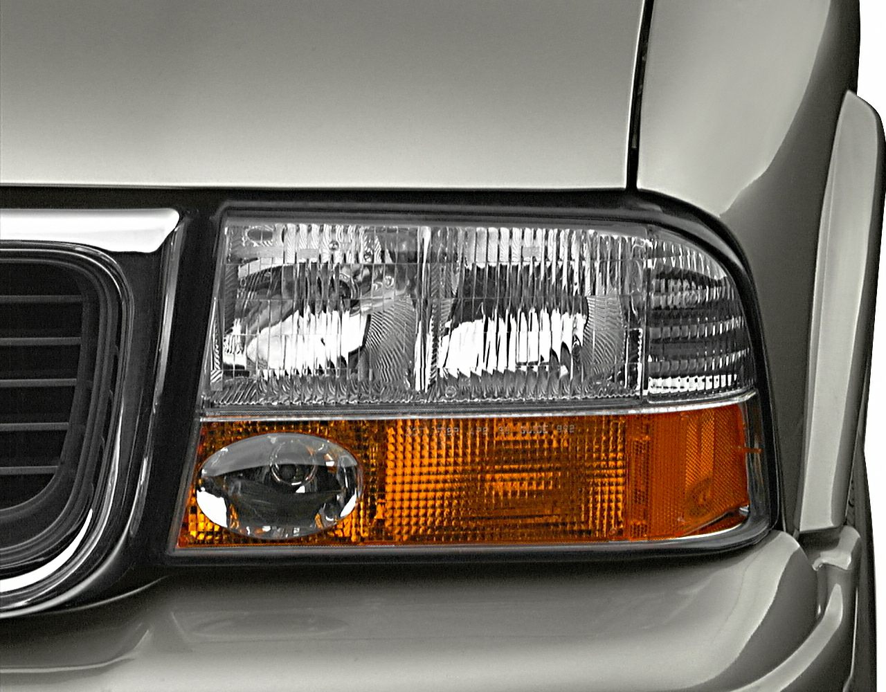 Close-up of vehicle headlight and amber turn signal cluster