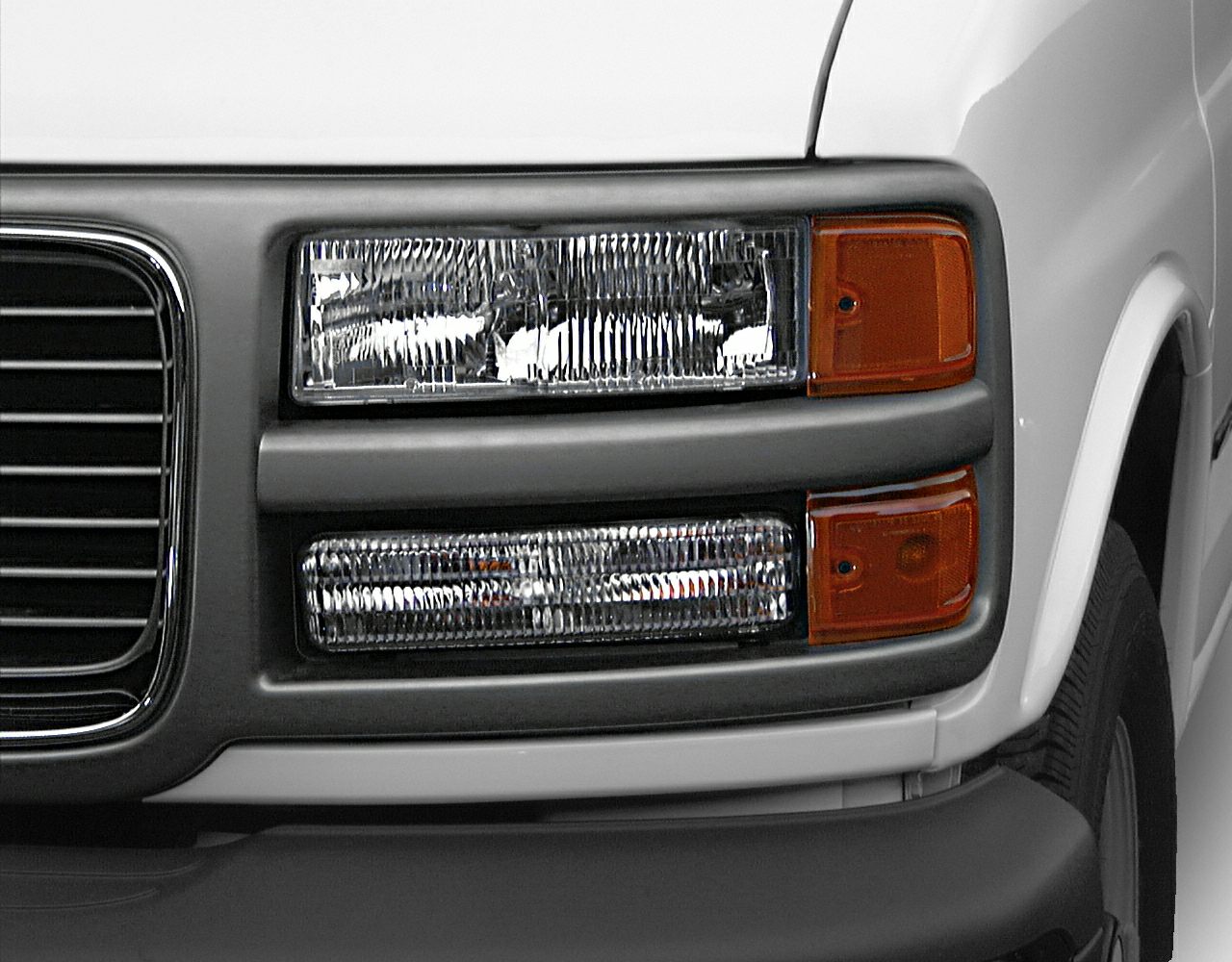 Close-up of a double-layered rectangular headlight and amber side indicator on a white vehicle front.