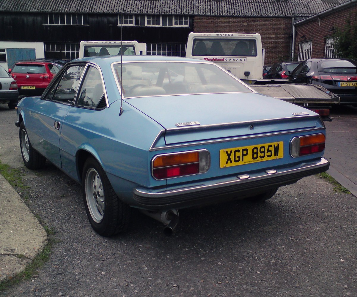 Blue vintage two-door coupe rear view with classic taillights and metal bumper
