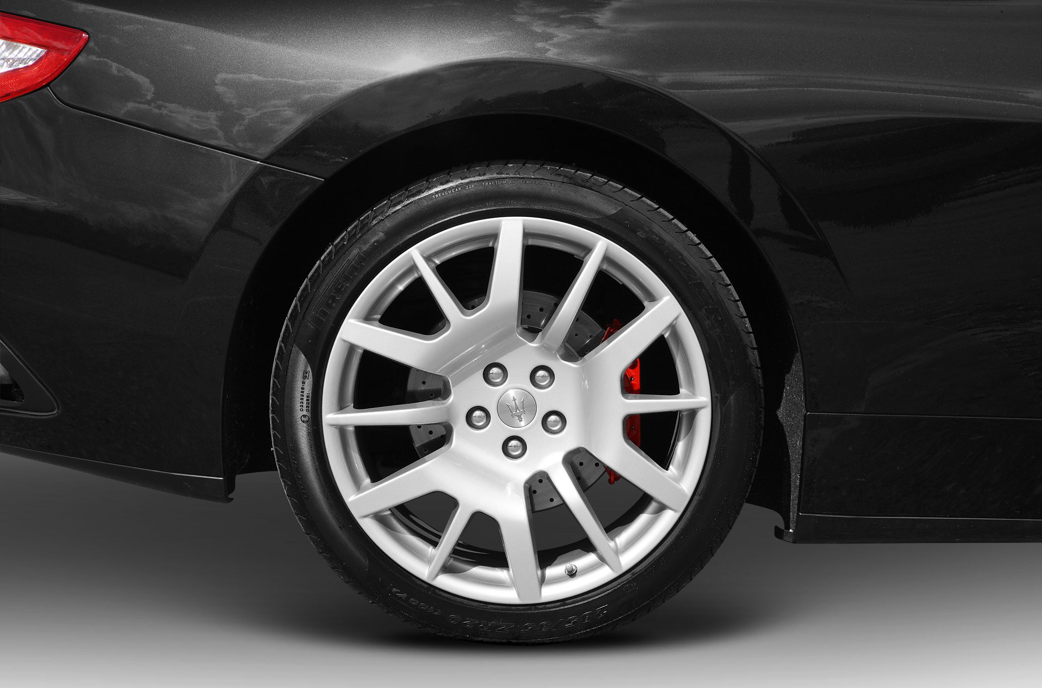 Silver alloy wheel with red brake caliper on a black car side