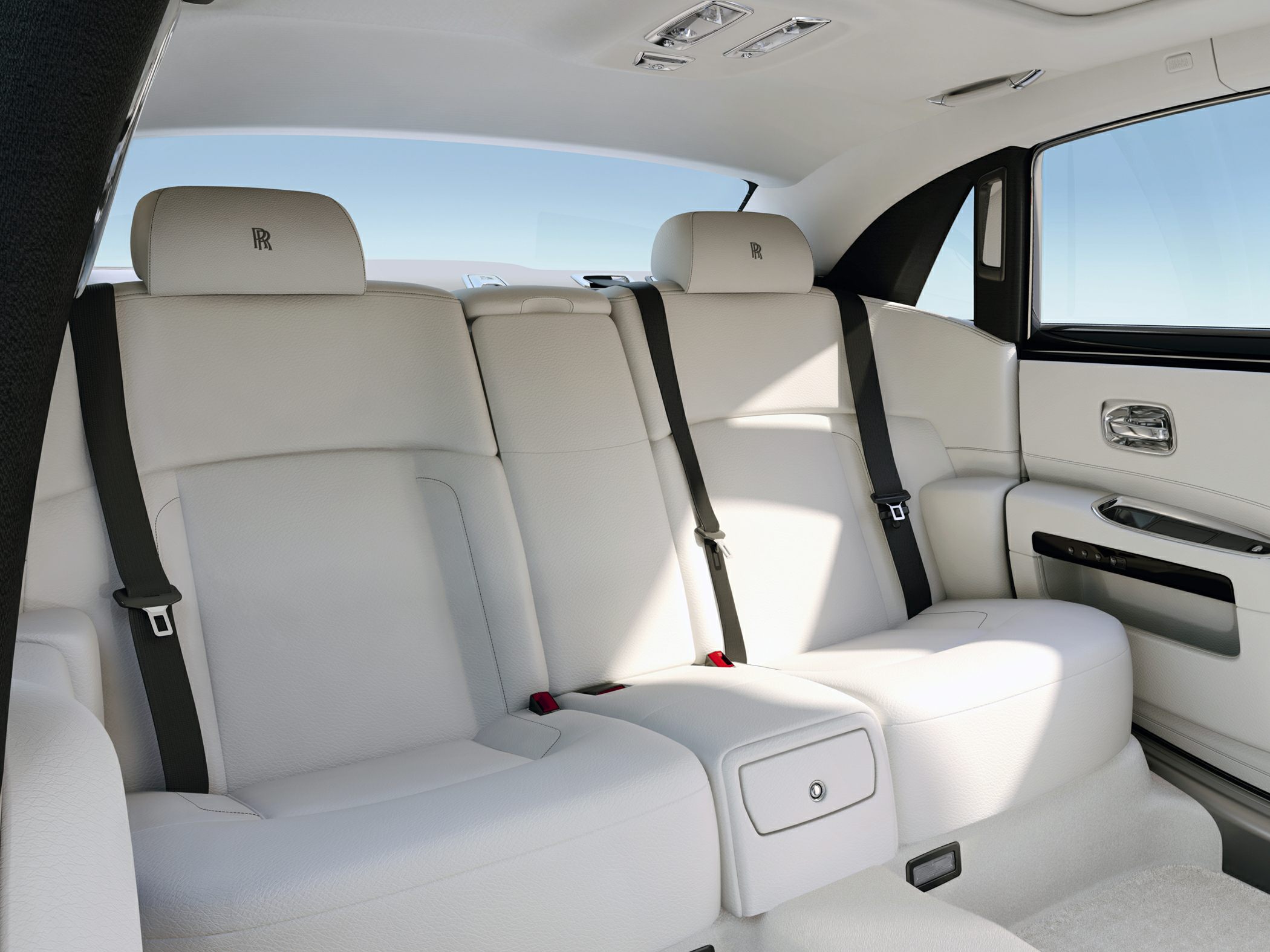 Luxury rear seating with white leather upholstery and seat belts.