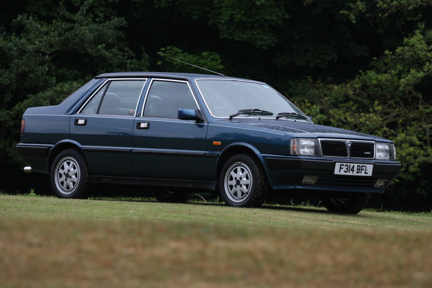 Side view of vintage 1980s sedan with square headlights and distinctive front grille.