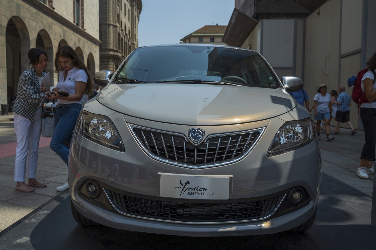 Close-up of car front grille and dual headlights in urban setting