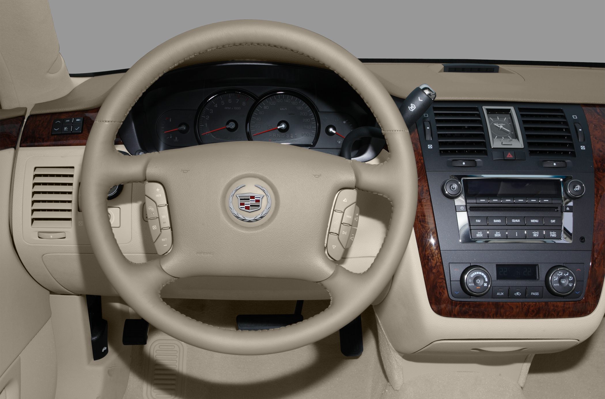 Beige steering wheel and dashboard with wood trim and control buttons.
