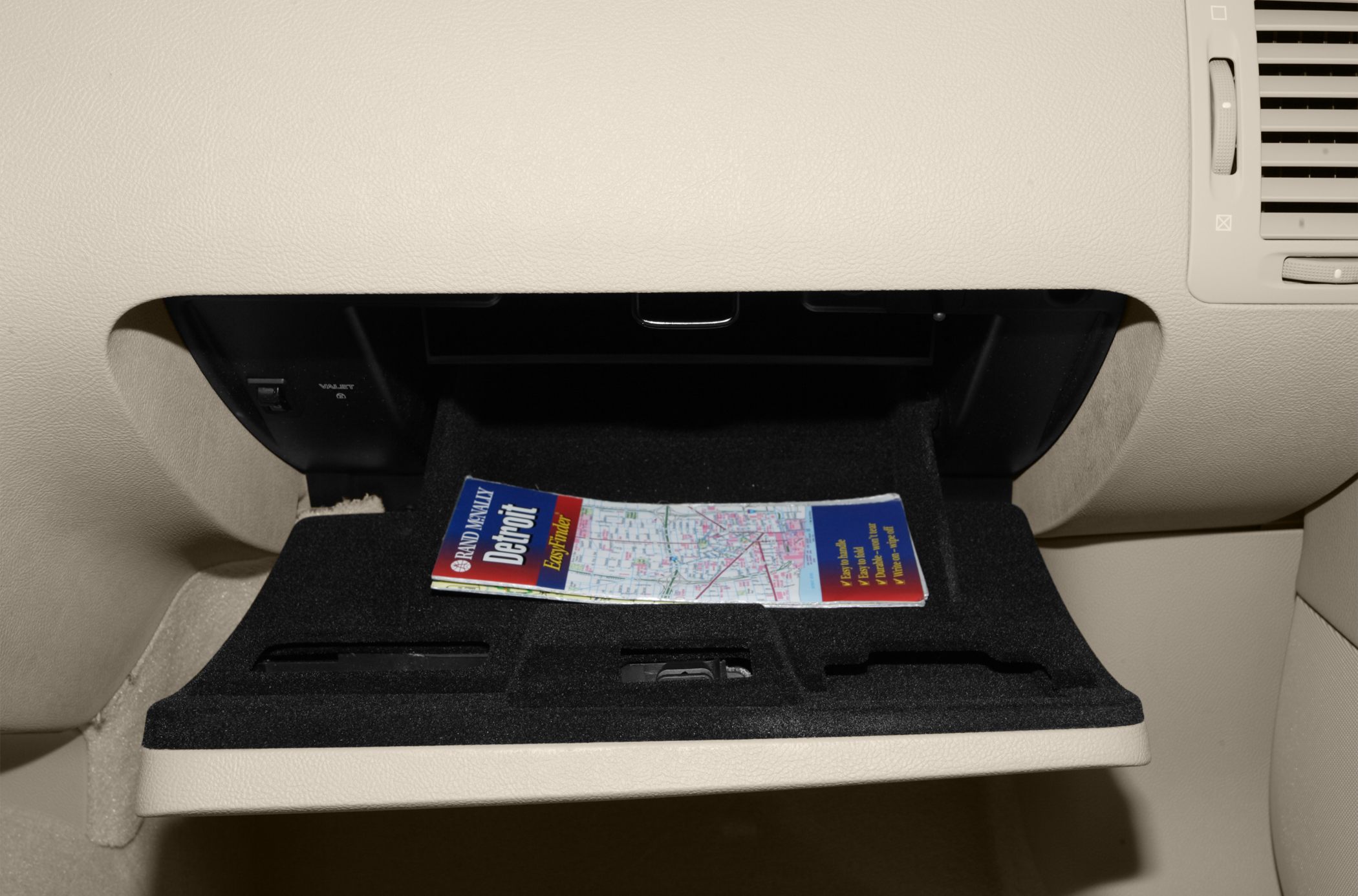 Open glove box interior with a Detroit map inside on beige car interior