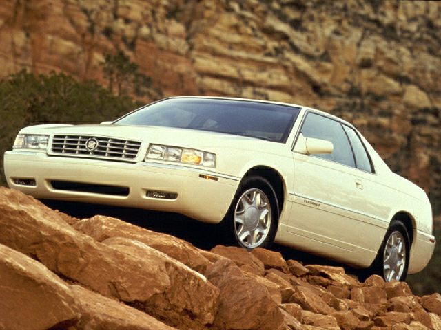 White coupe with chrome grille and sleek body on rocky terrain