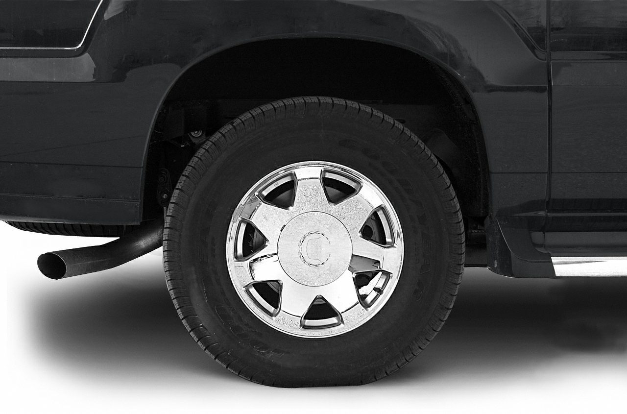 Chrome alloy wheel with visible tire tread and rear exhaust pipe on pickup truck