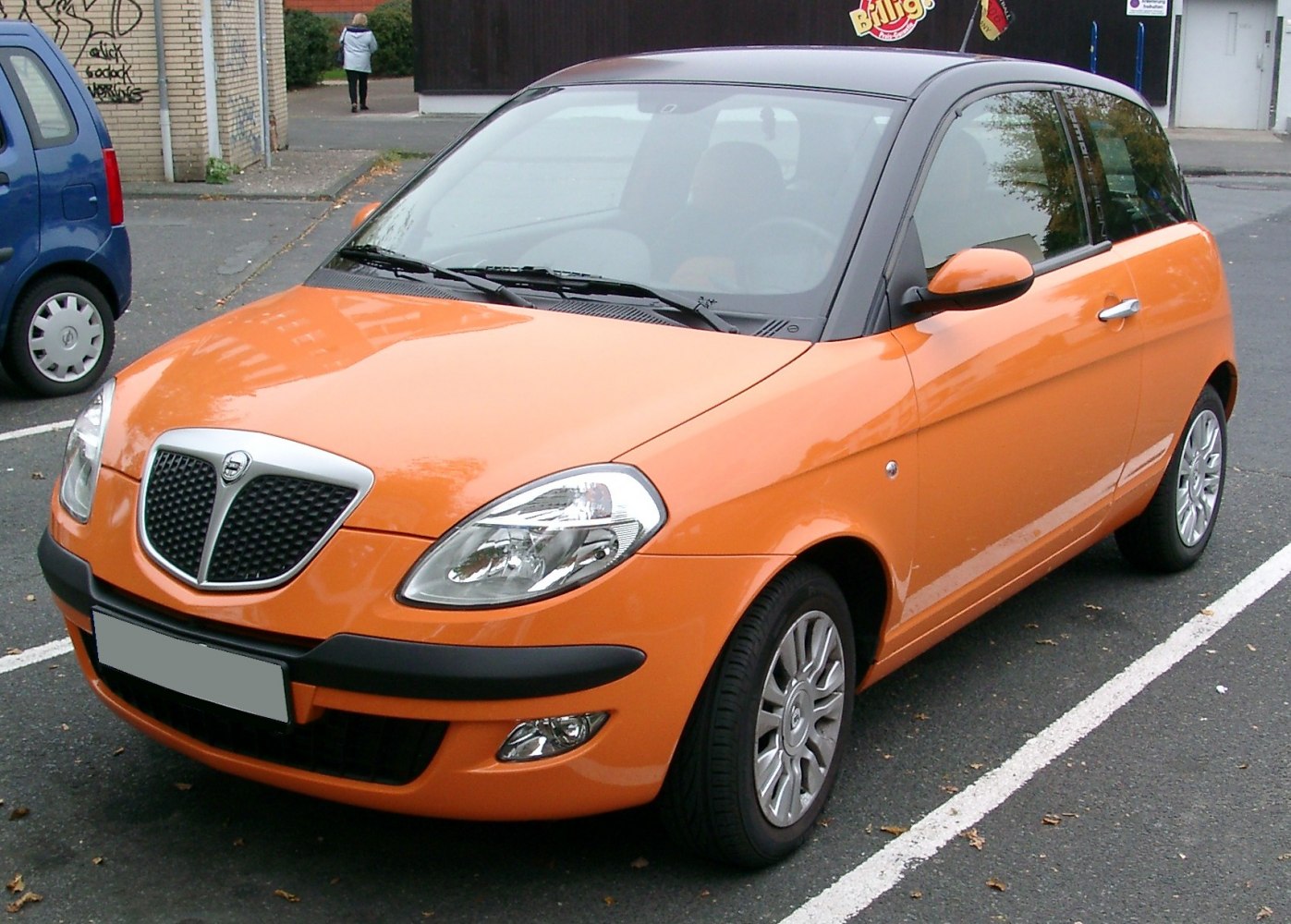 Orange compact hatchback with distinctive front grille and two-door design