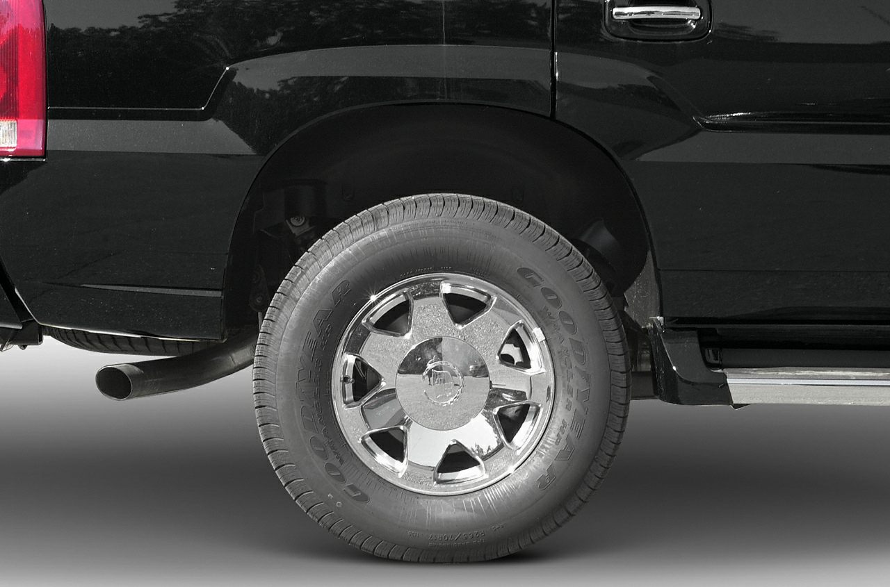 Close-up of rear wheel with chrome rim and exhaust pipe on black SUV.