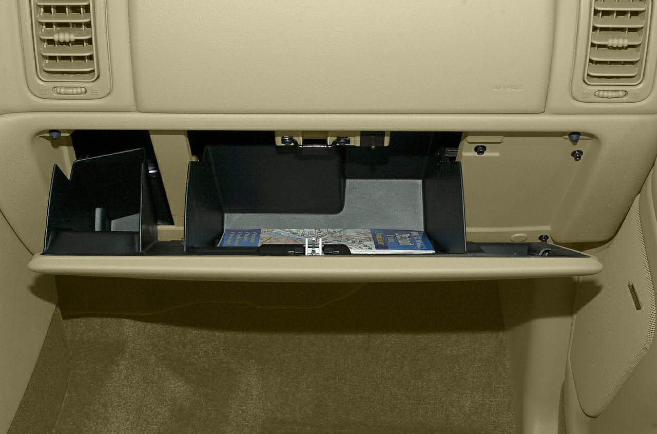 Beige open glove box storage compartment with air vents and dashboard section.