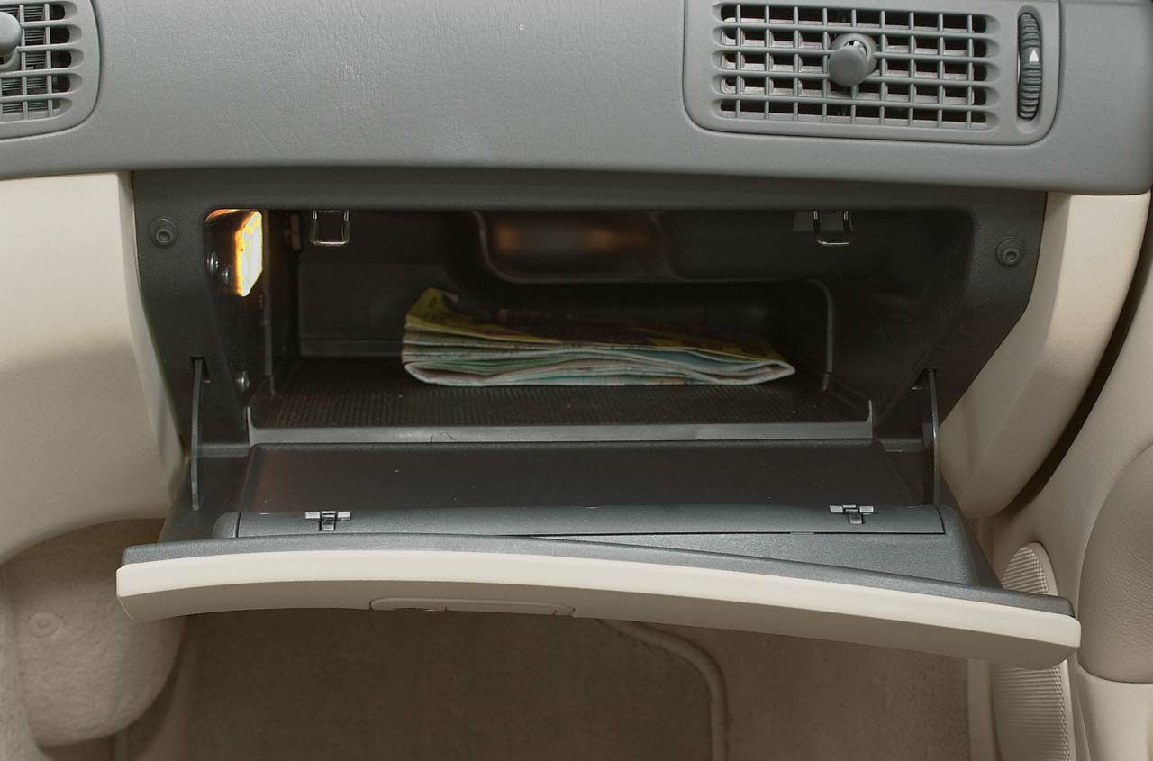 Open glovebox with documents inside under car dashboard.