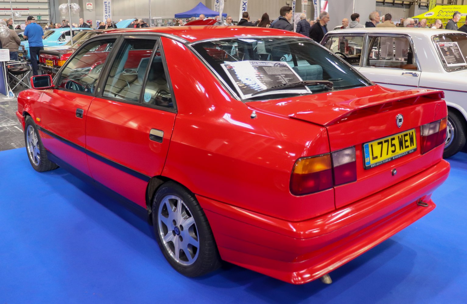 Red four-door sedan with rear spoiler and alloy wheels