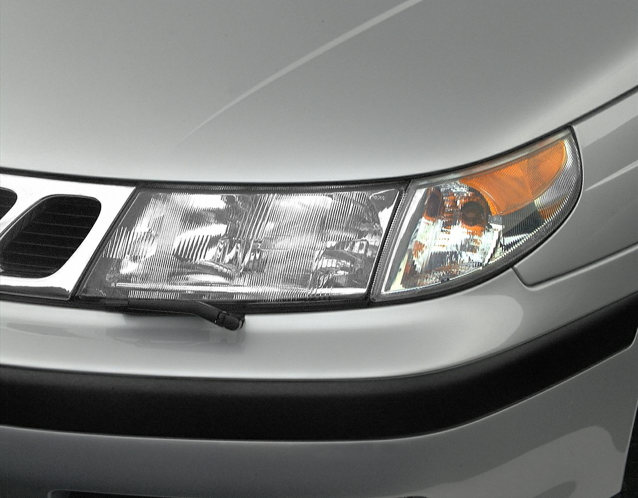 Close-up of a car headlight and adjacent grille segment