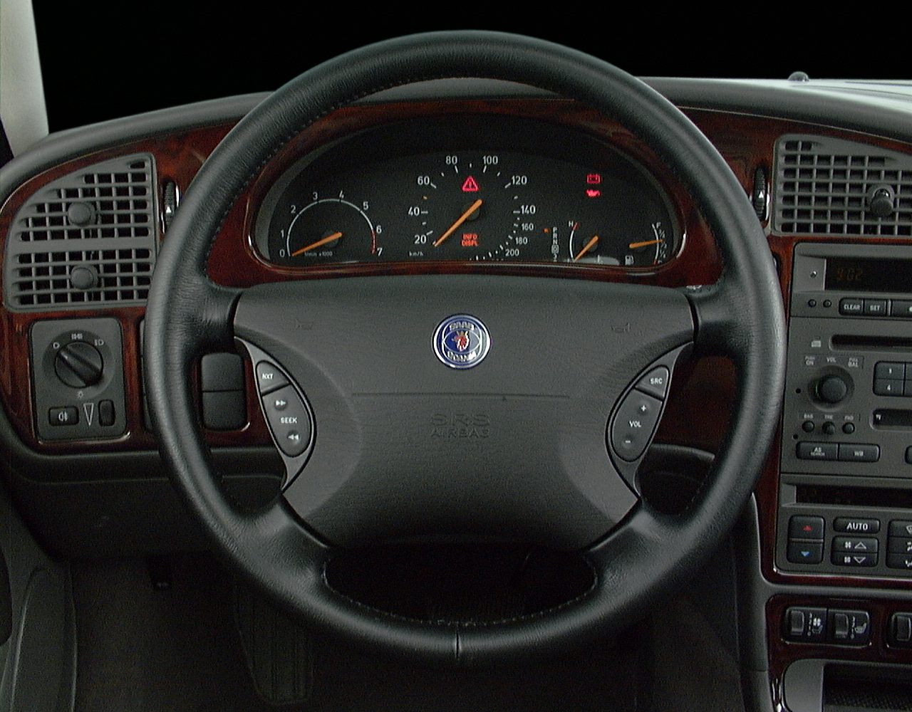 Steering wheel with Saab emblem and classic dashboard including instrument cluster and wood trim