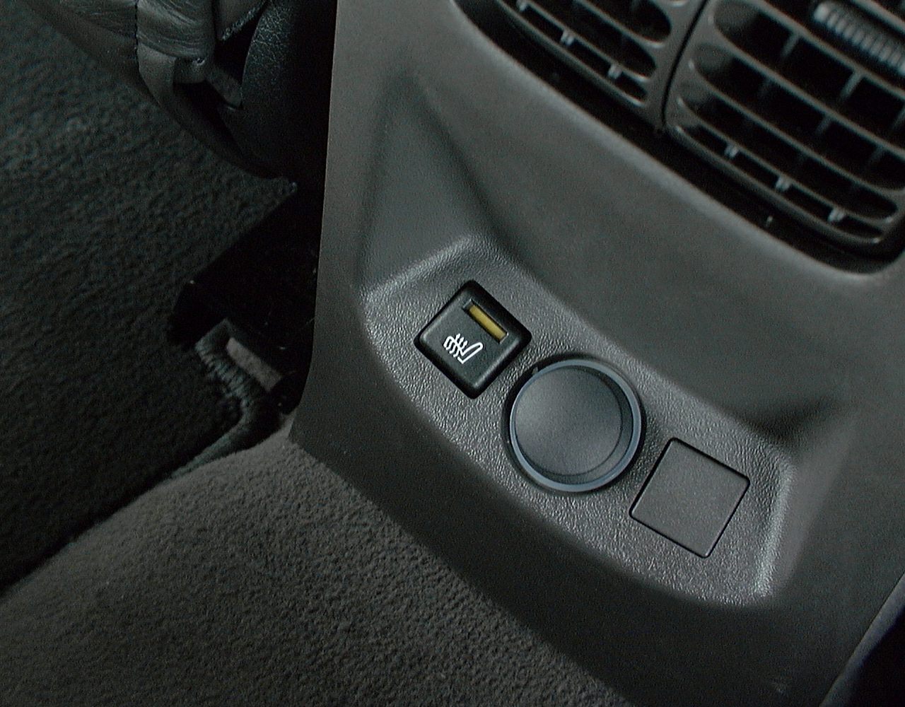 Close-up of rear seat heating switch and air vent in car interior