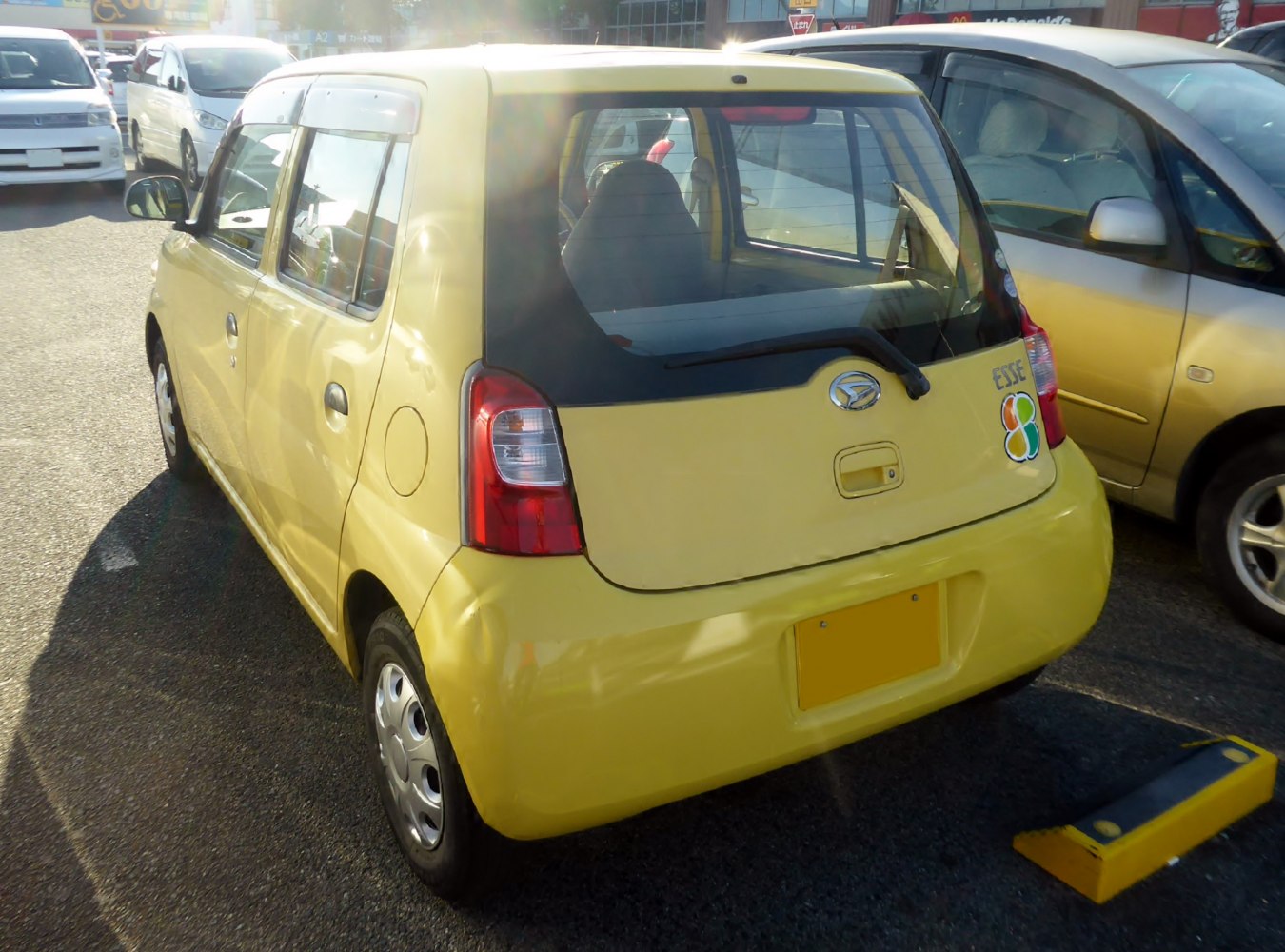 Rear view of compact yellow kei hatchback with vertical lights and rear wiper