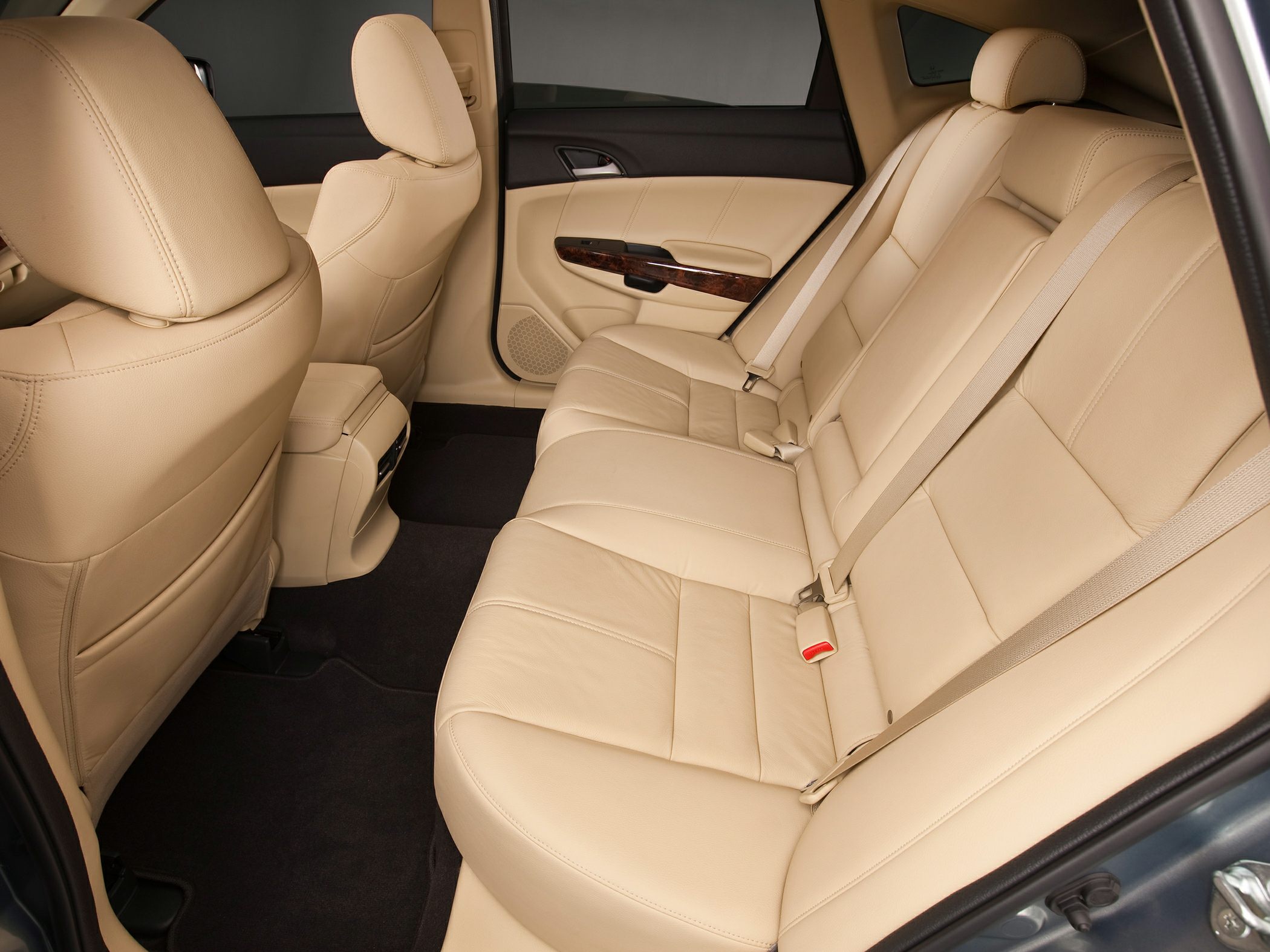 Spacious beige leather rear seats with wood-trimmed door panel and seat belts