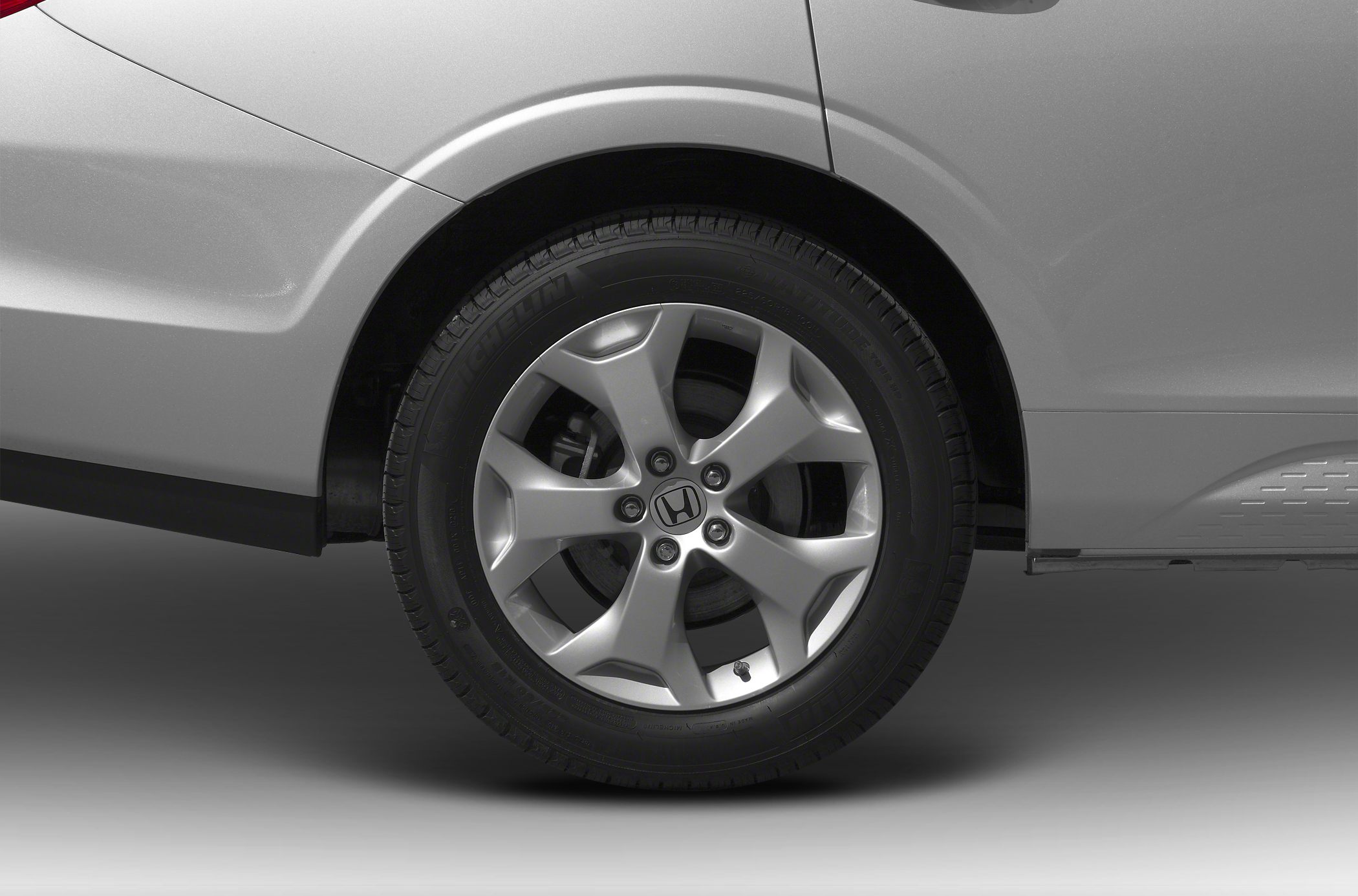 Five-spoke alloy wheel and tire close-up on vehicle rear side