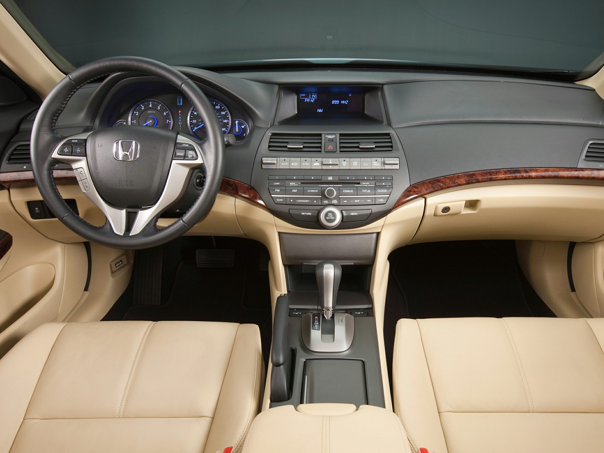 Interior dashboard, steering wheel, beige leather seats, center console, wood trim