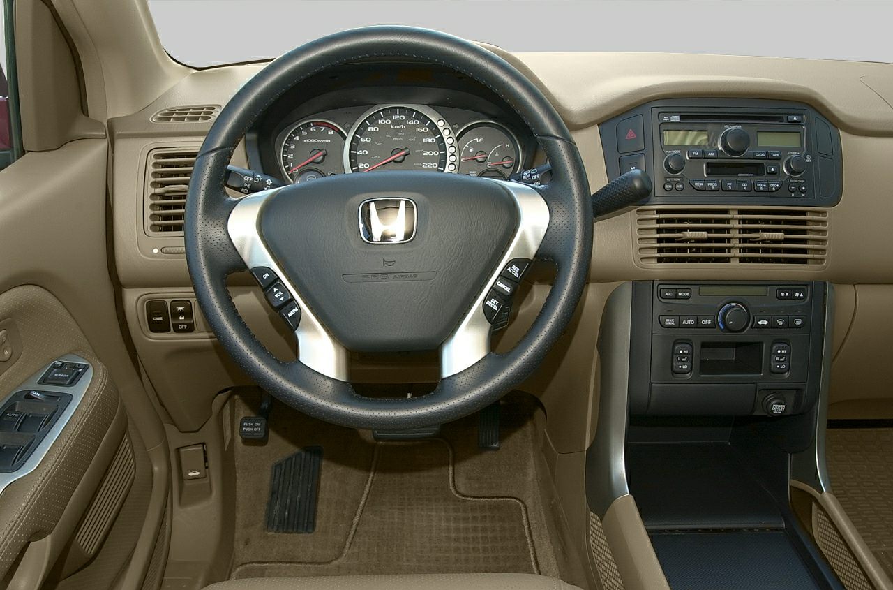 Steering wheel with control buttons and beige car dashboard with analog gauges