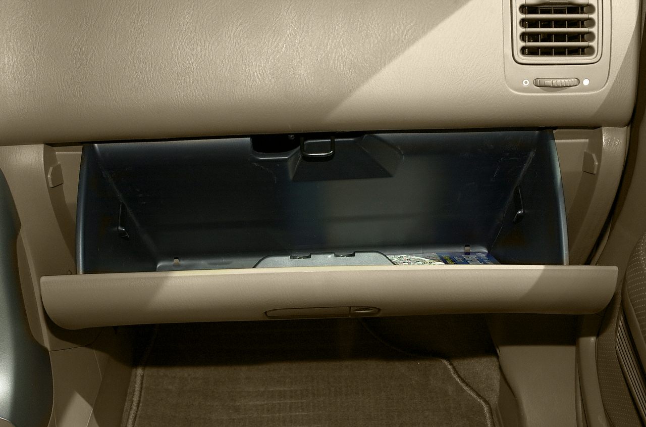 Open glove compartment in beige car dashboard.
