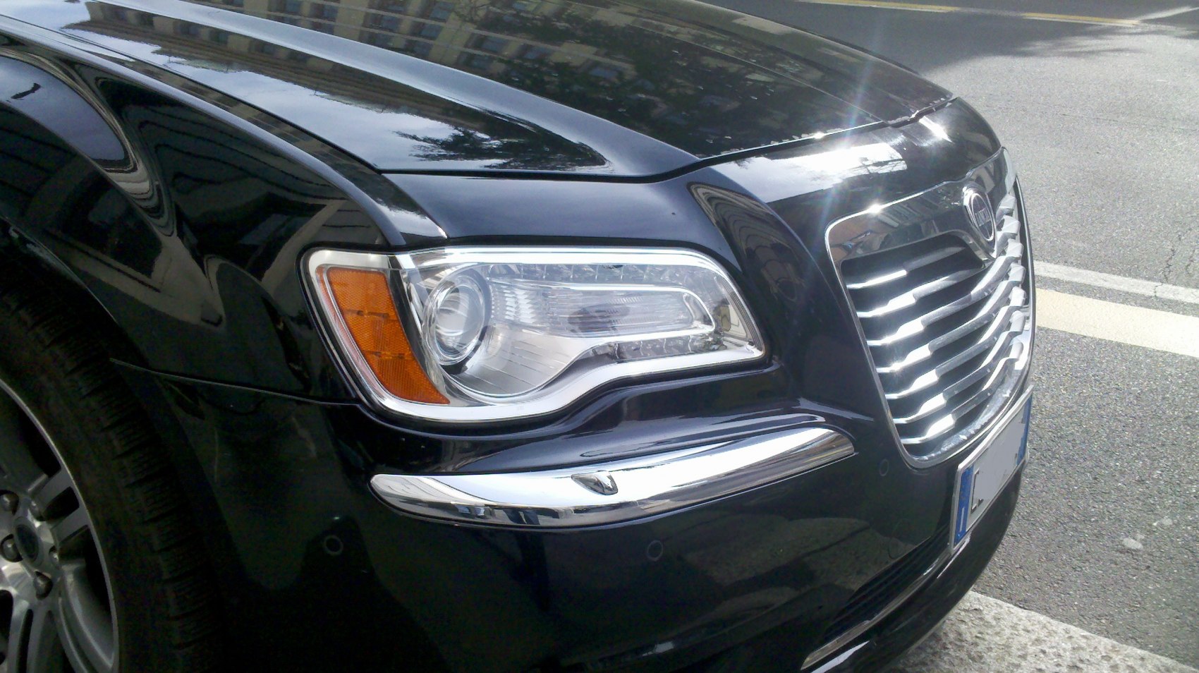 Close-up of luxury sedan front grille and modern headlight.