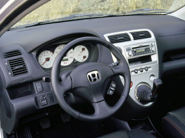 Steering wheel and dashboard with white gauge cluster and manual gear shift