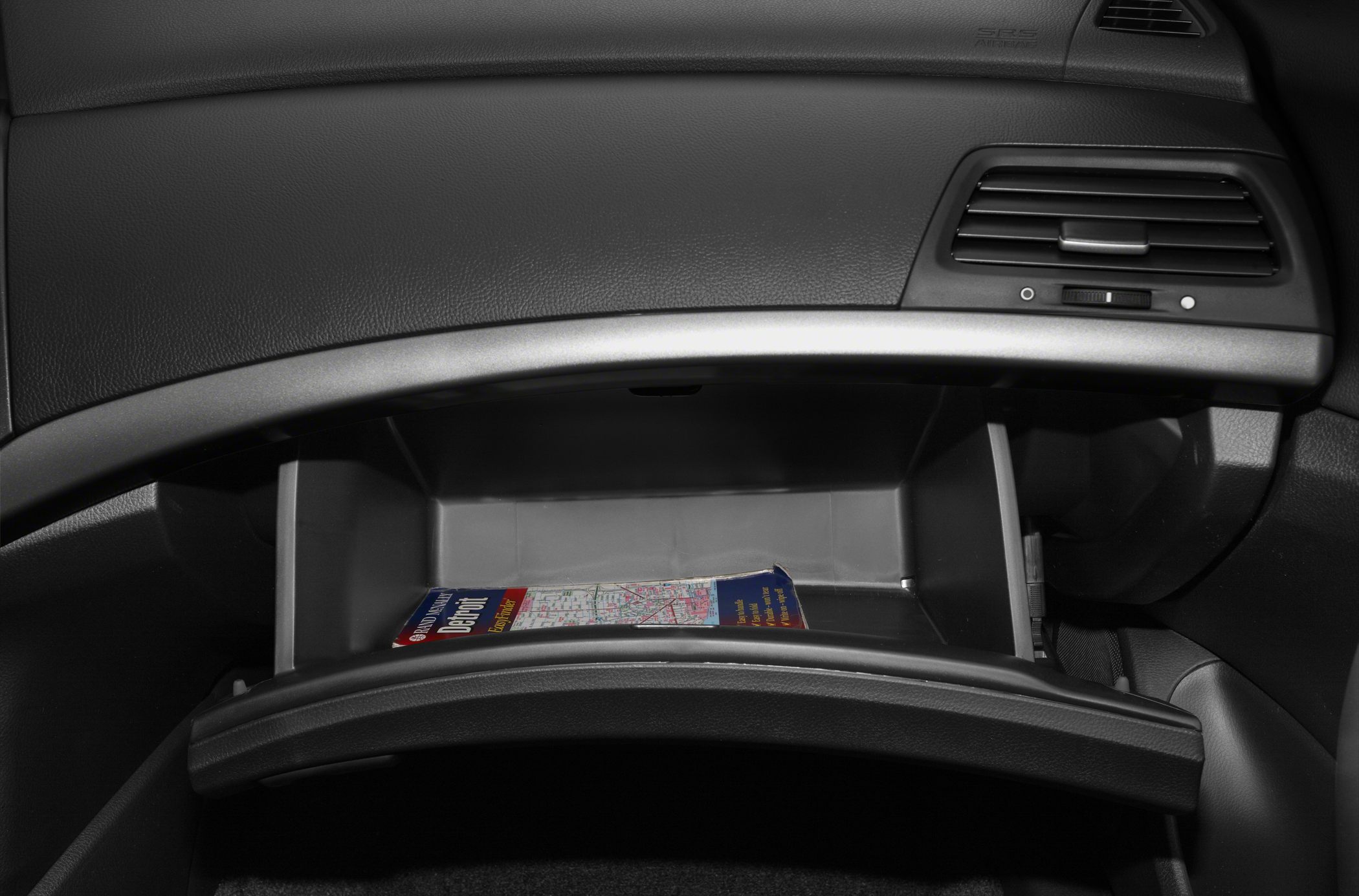 Open glove compartment with map inside and dashboard air vent