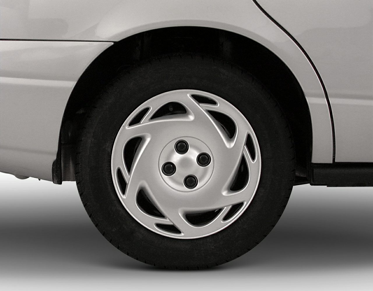 Close-up of silver hubcap and wheel with four-lug pattern