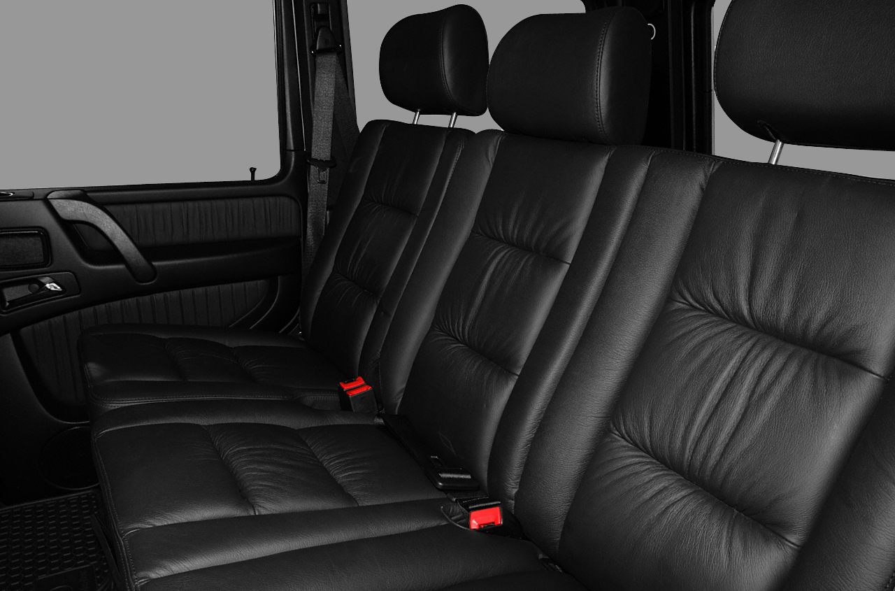 Black leather rear seats with headrests and seat belts in vehicle interior