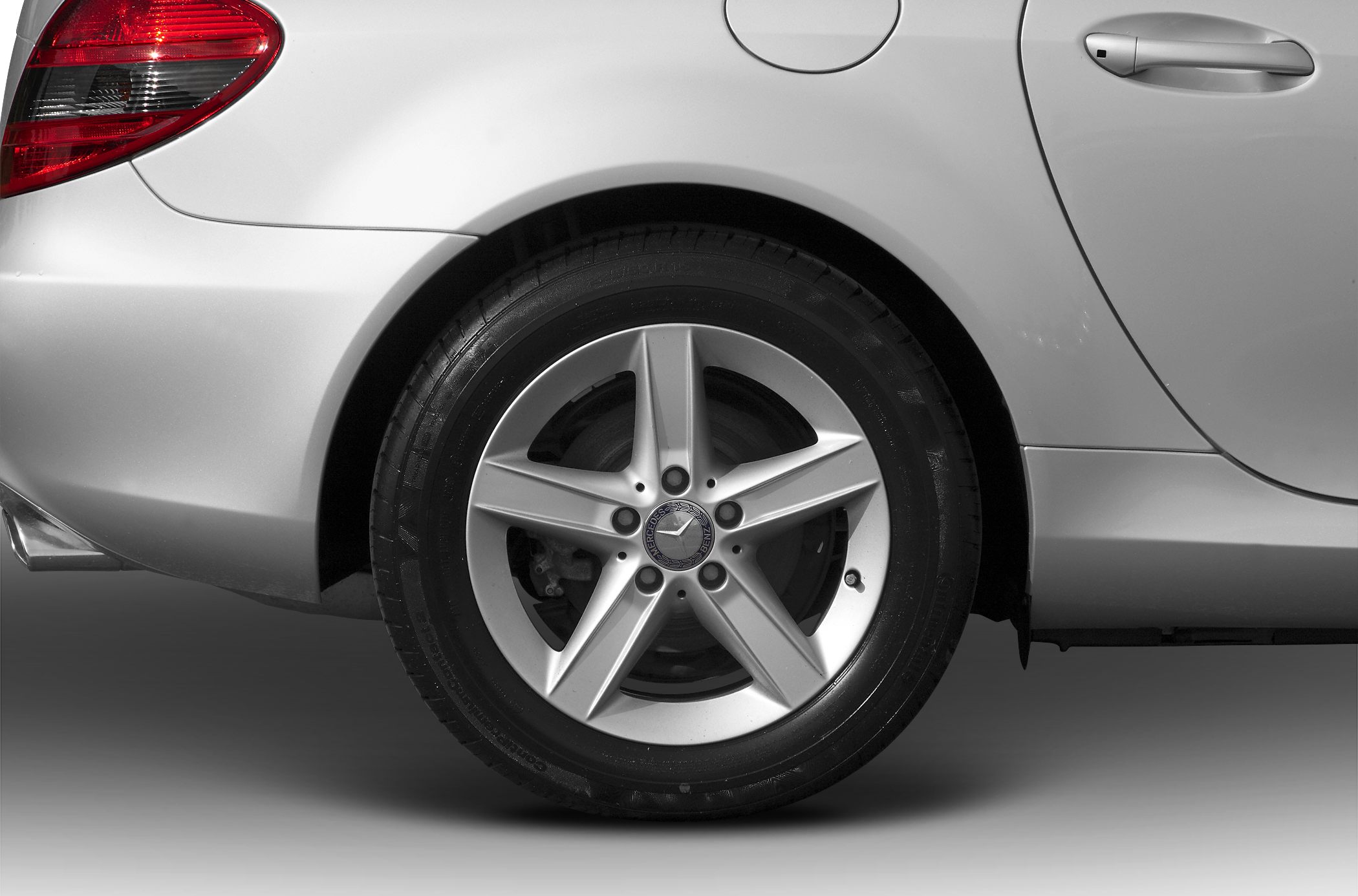 Close-up of a luxury car's rear alloy wheel and quarter panel