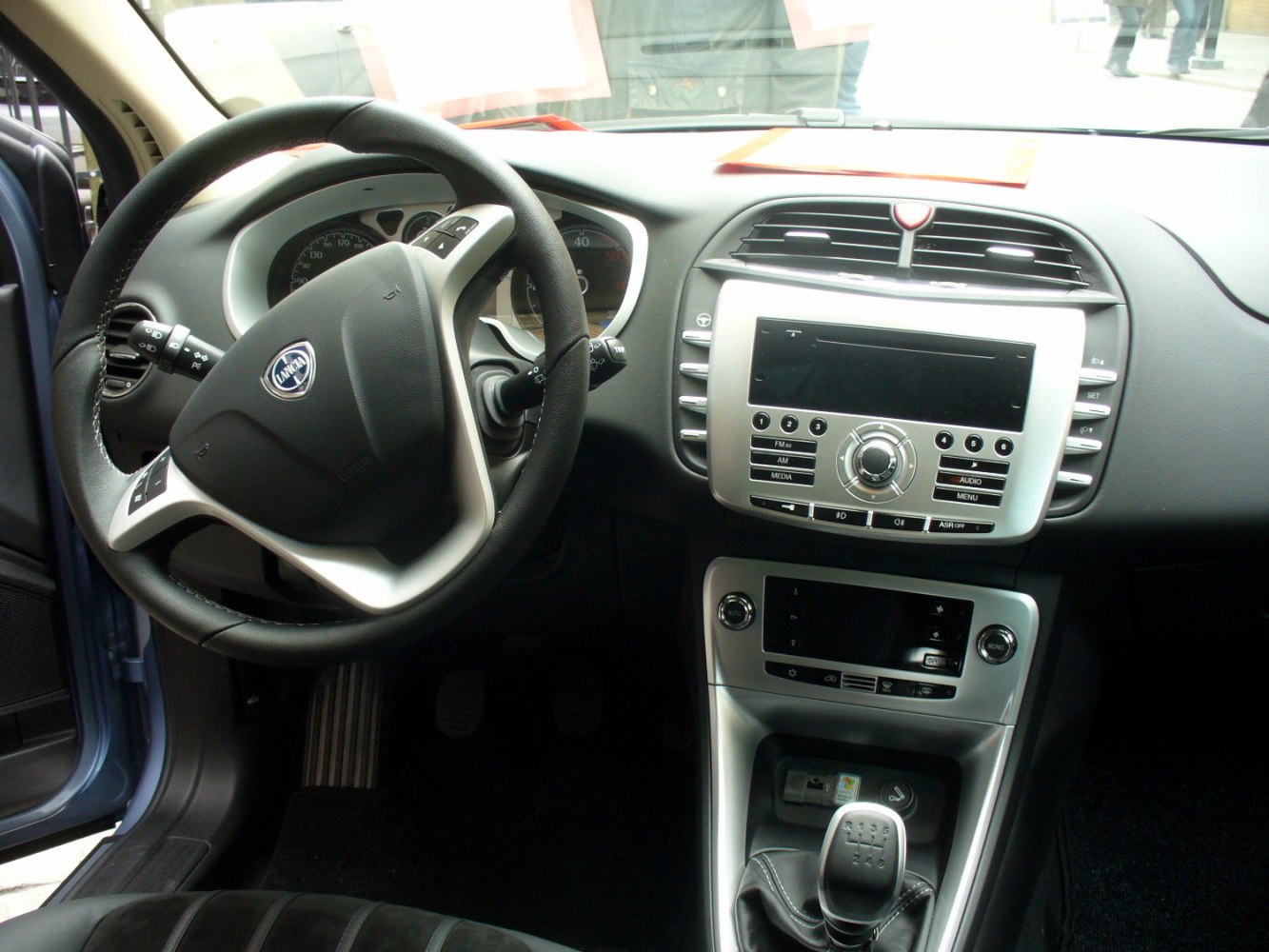 Steering wheel, dashboard controls, and manual gear shift in car interior