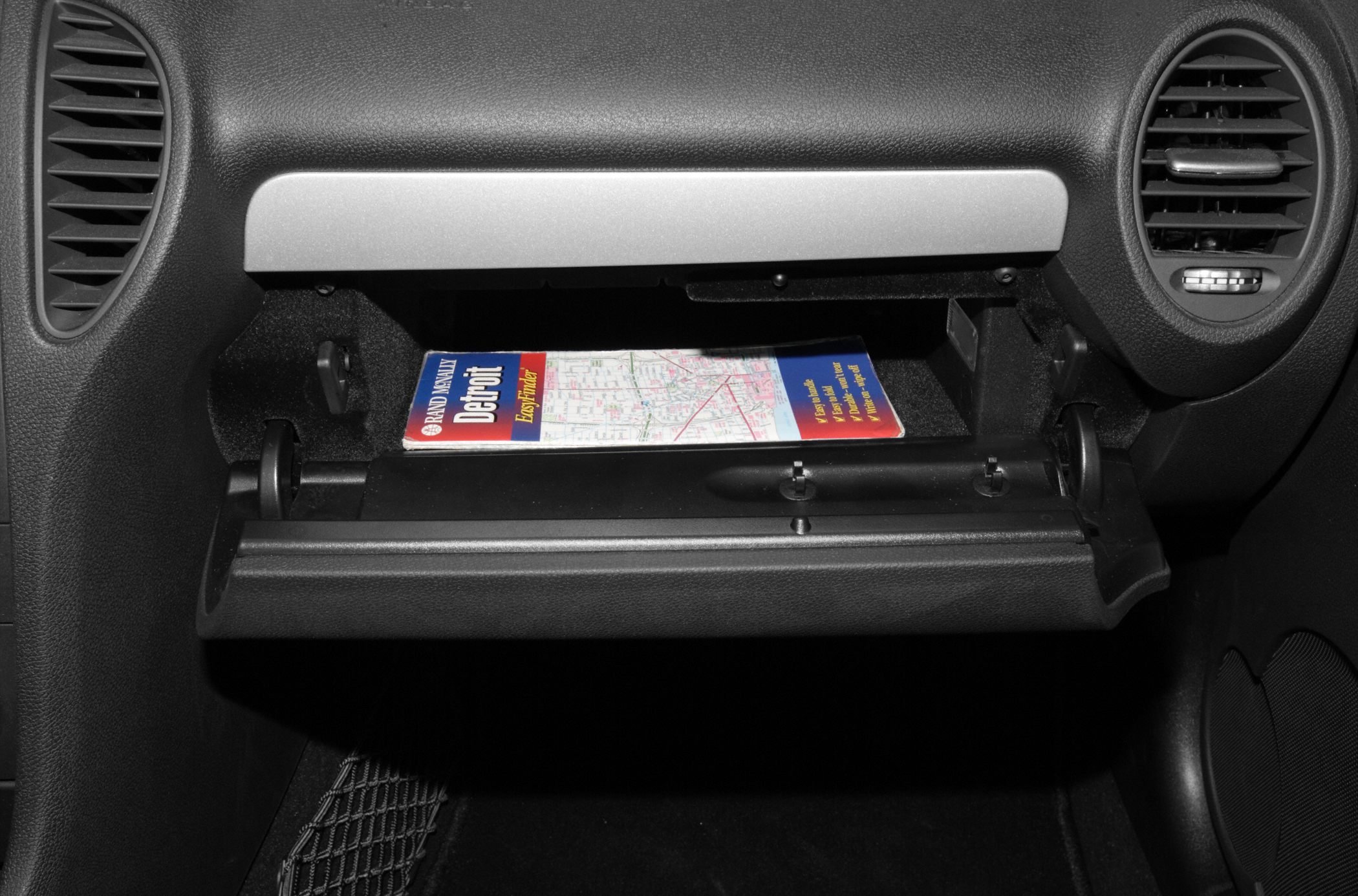 Open glove compartment with a Detroit map inside and visible dashboard air vents