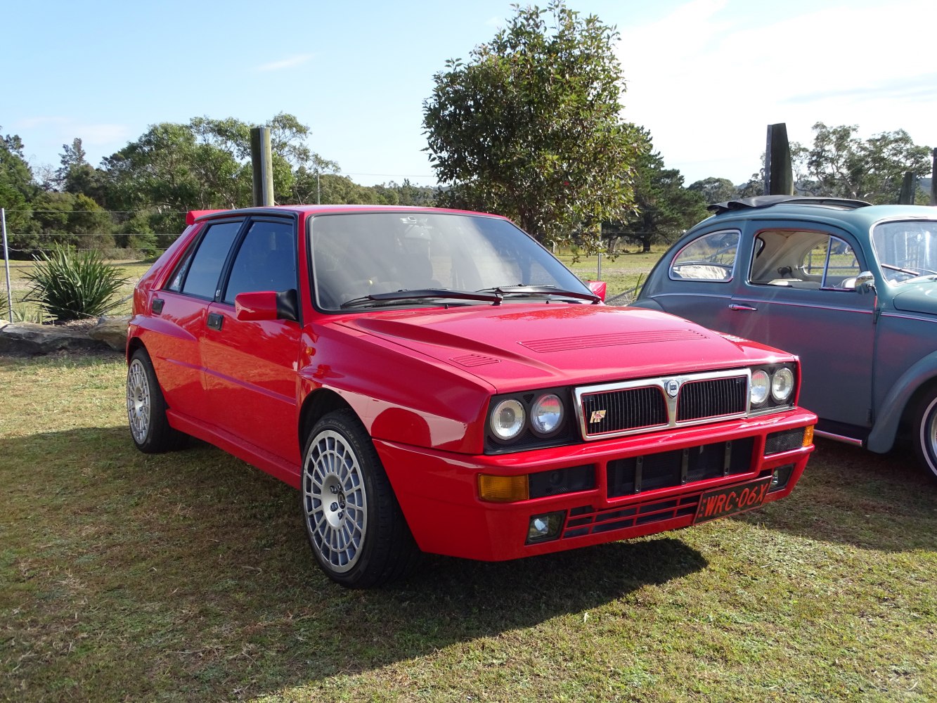 Red rally hatchback with quad headlights and unique front grille