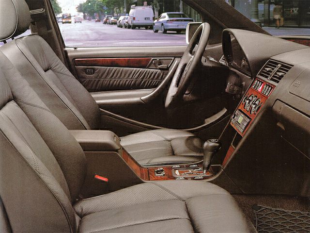 Interior view with seats, dashboard, steering wheel, center console, and wood trim.